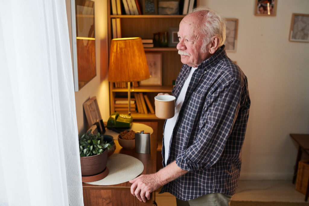senior man with mug of tea standing in front of wi 2022 01 31 14 58 59 utc