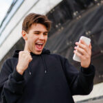 cheerful man holding smartphone and celebrate win 2022 09 28 22 52 54 utc