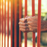 male hands behind prison yard bars 2021 08 26 23 02 46 utc