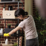 domestic employee dusting shelves in urban apartme 2022 11 09 03 22 33 utc