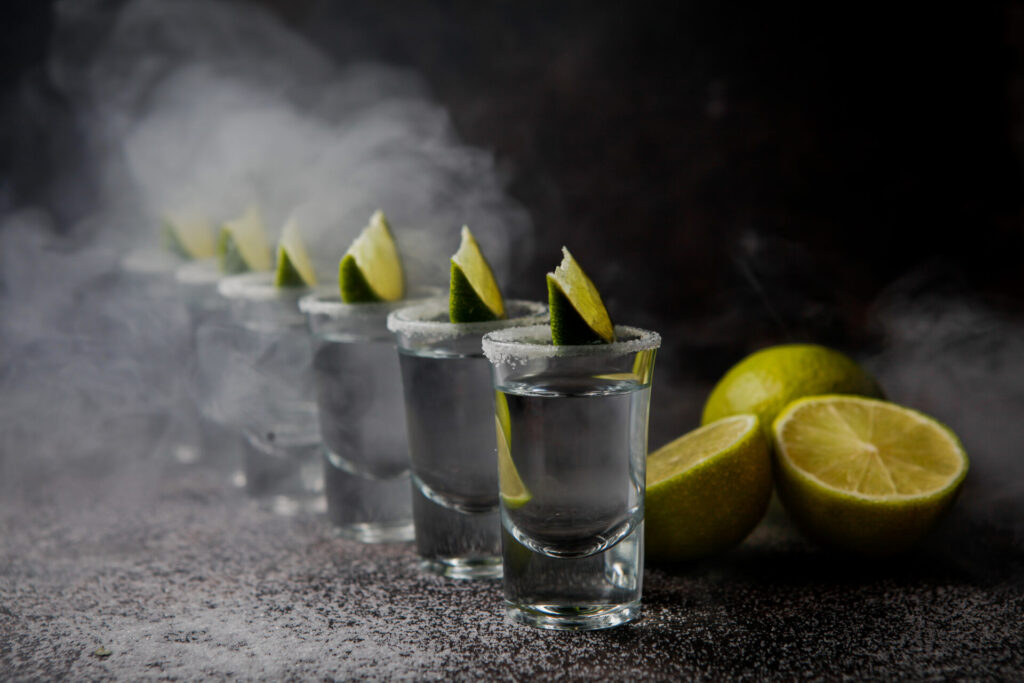 side view tequila in glass served with limes and salt