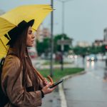 woman using a smartphone and holding yellow umbrel 2022 03 29 07 09 34 utc