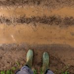 farmer in rubber boots standing on muddy dirt road 2021 08 26 23 03 13 utc