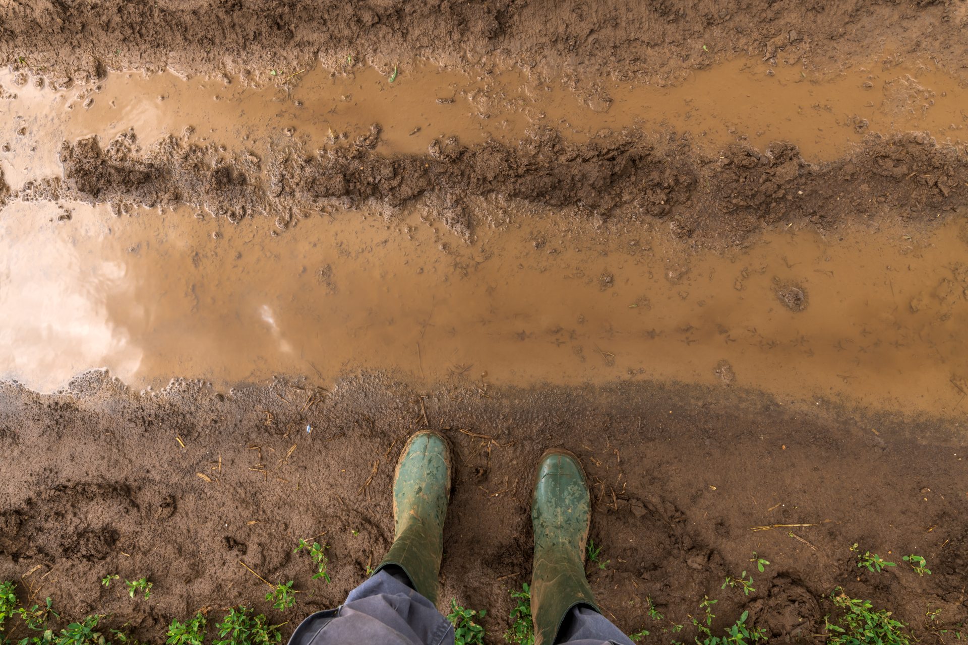 farmer in rubber boots standing on muddy dirt road 2021 08 26 23 03 13 utc