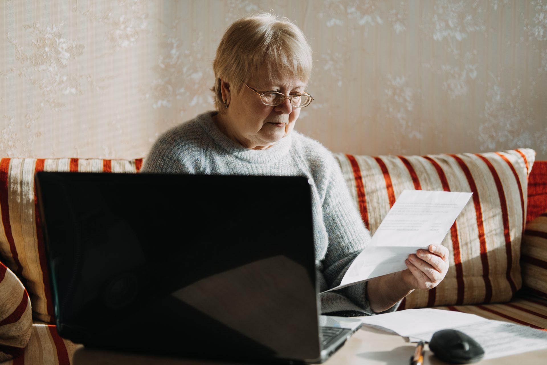 senior woman using laptop and holding documents at 2021 08 30 20 32 15 utc