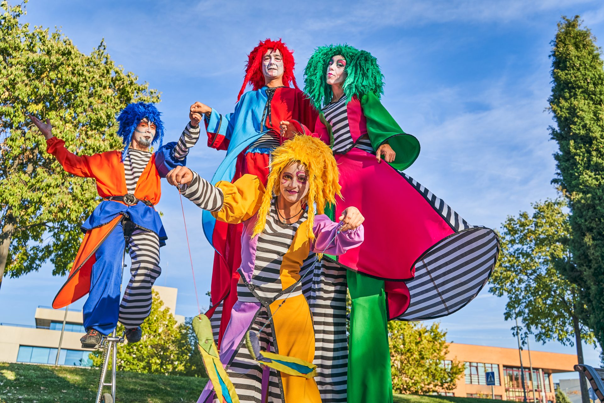 cheerful harlequins on stilts and unicycle in park 2022 11 19 08 13 58 utc