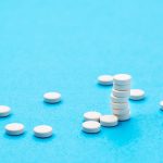 white round pills in a stack and next on a blue ba 2022 06 21 18 11 08 utc