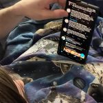millennial in recliner balancing phone on stomach 2022 11 07 07 35 45 utc