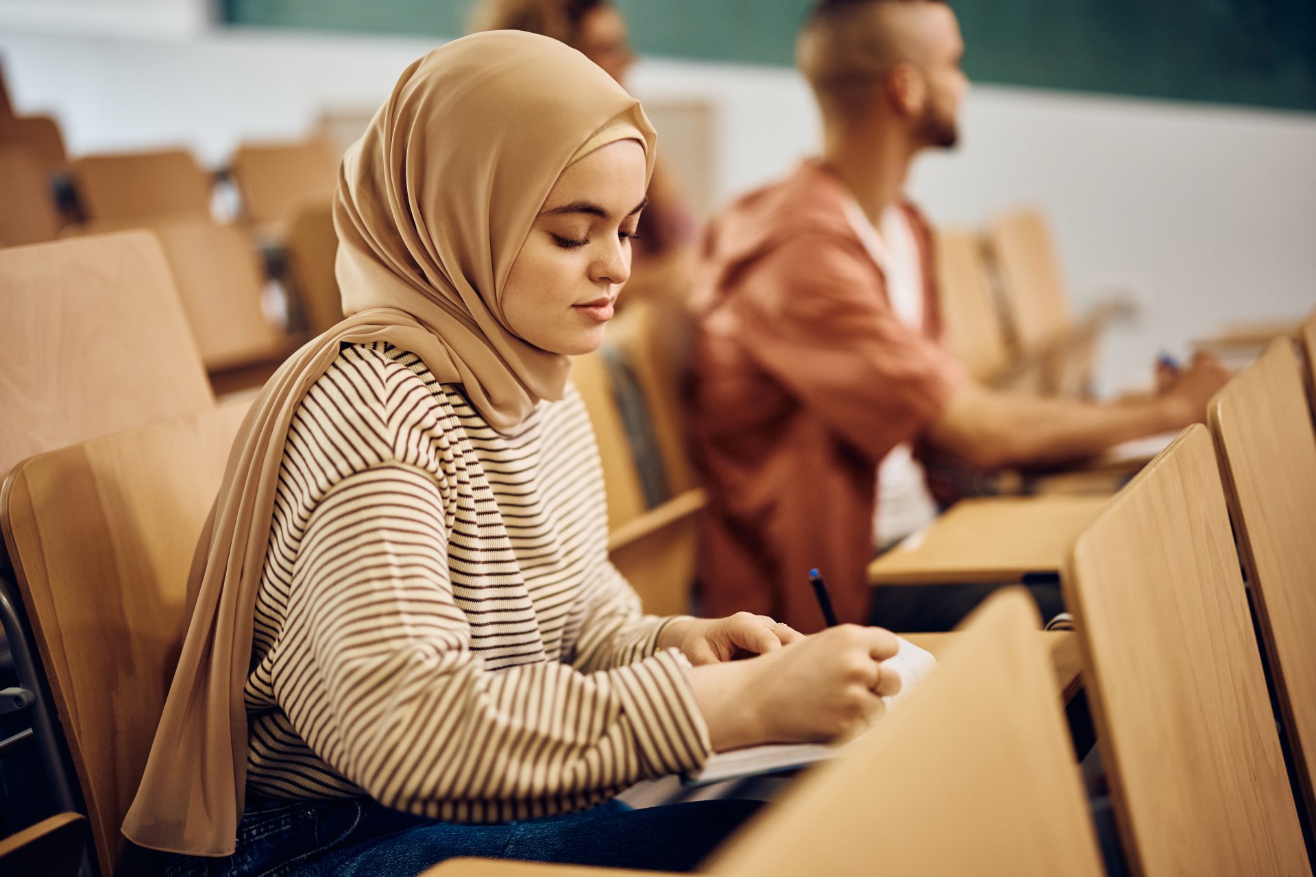 young woman wearing hijab while taking notes durin 2022 12 06 01 01 38 utc