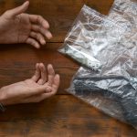 handcuffed hands of criminal suspect on wooden tab 2022 11 14 15 59 16 utc