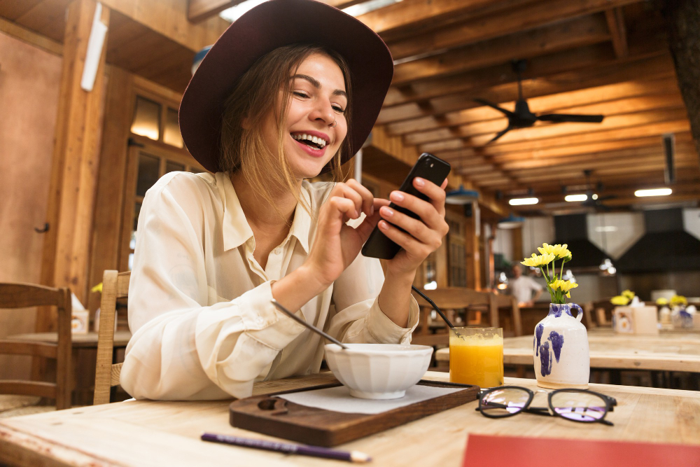 portrait charming woman wearing hat using cell phone while sitting