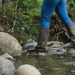 migrant woman crossing a stream wearing blue jeans 2023 11 27 05 12 13 utc