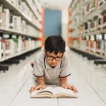 smart school boy reading a book at the library 2023 11 27 05 25 26 utc
