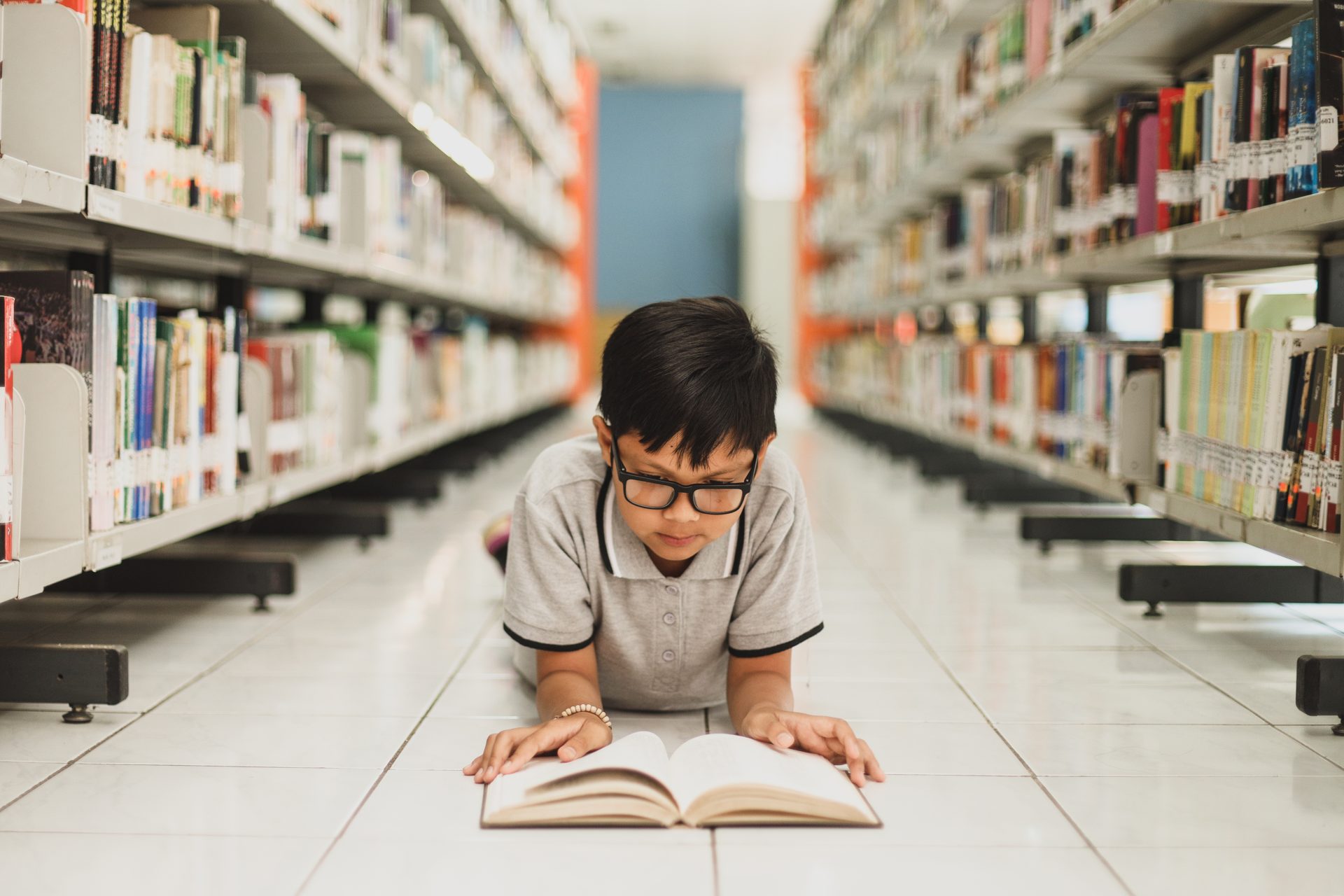 smart school boy reading a book at the library 2023 11 27 05 25 26 utc
