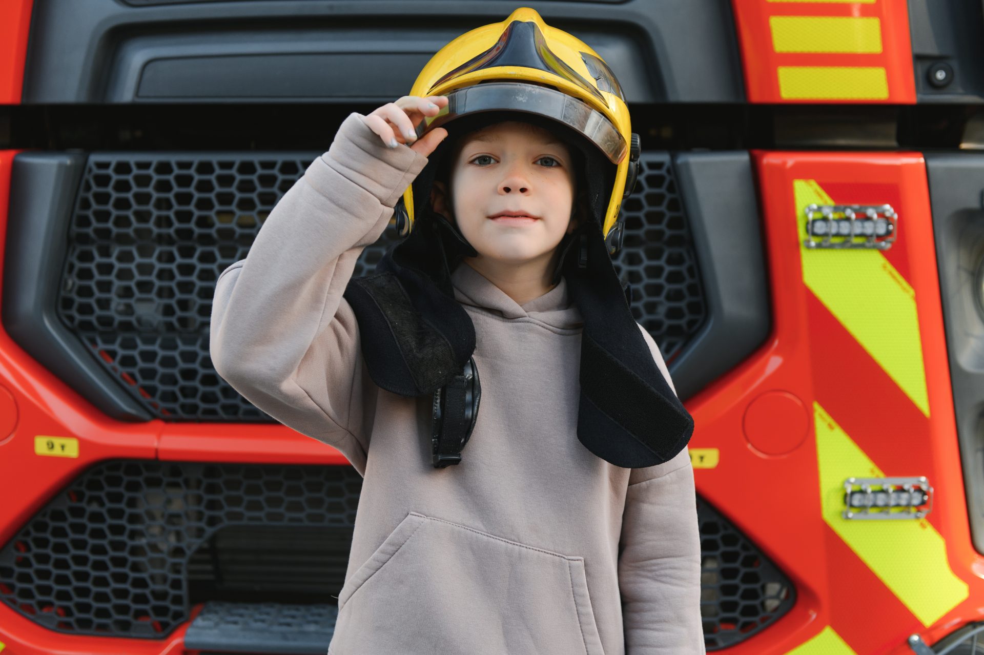 a boy wearing a fireman s helmet near a fire truck 2023 11 27 05 16 41 utc