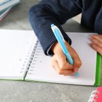 boy writes in a notebook on grey table space for 2023 11 27 05 33 08 utc