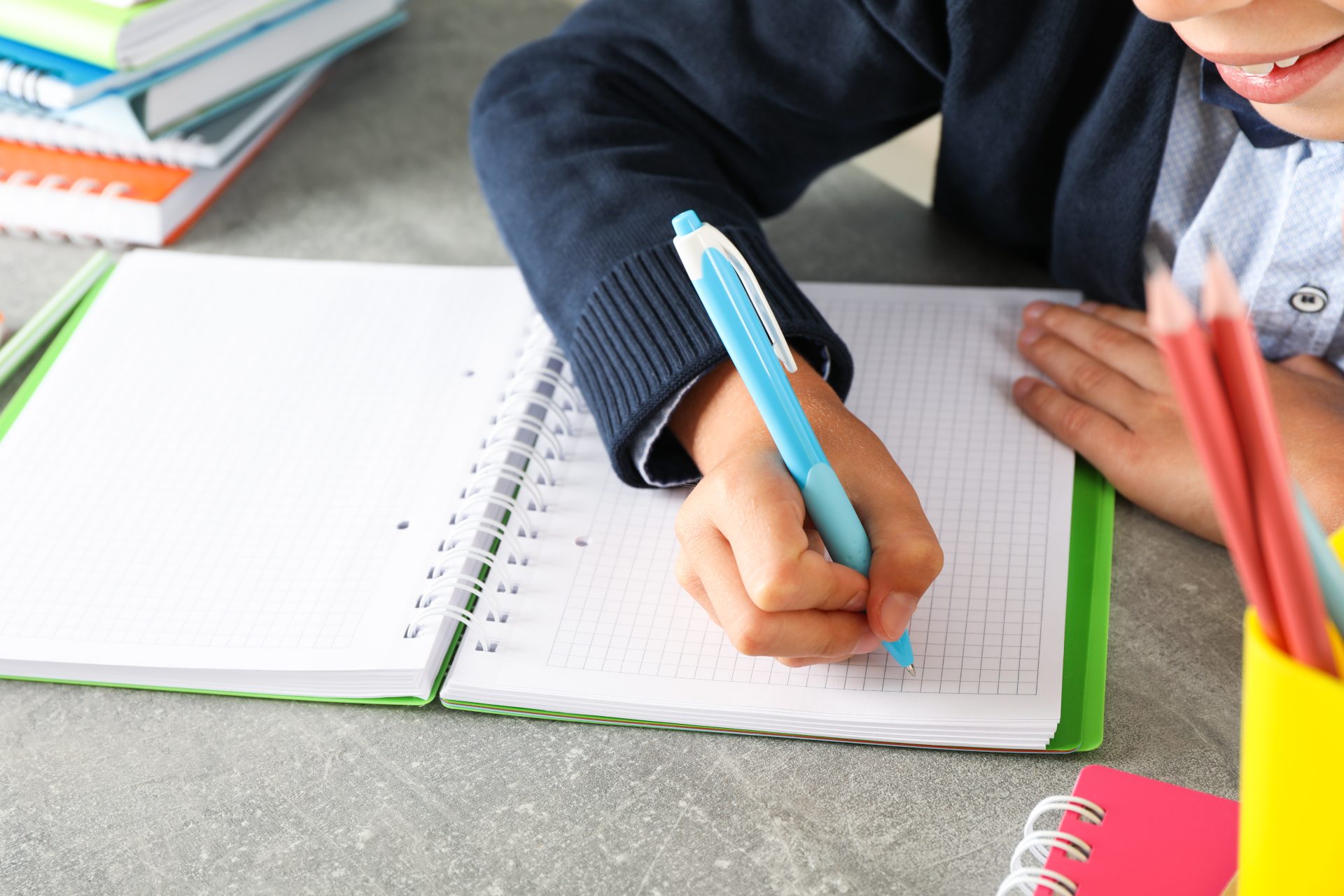 boy writes in a notebook on grey table space for 2023 11 27 05 33 08 utc
