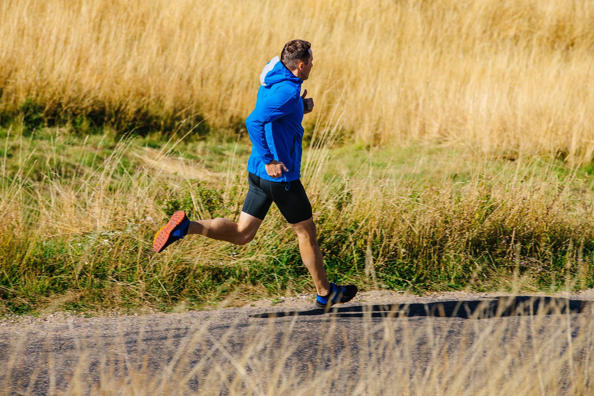 male runner running on road among dry grass 2023 11 27 05 27 34 utc