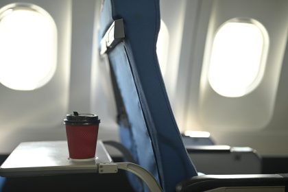 a red disposable coffee cup on airplane tray table 2024 12 05 20 30 25 utc