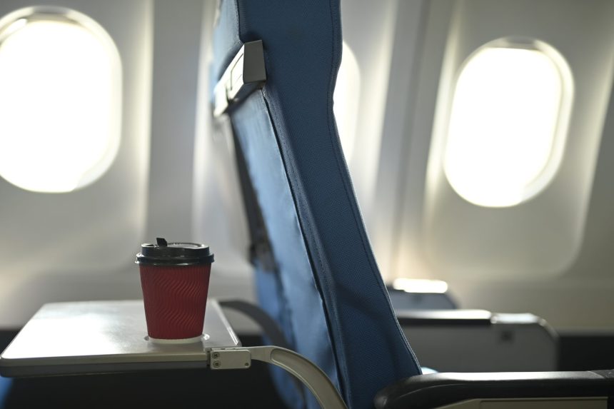 a red disposable coffee cup on airplane tray table 2024 12 05 20 30 25 utc
